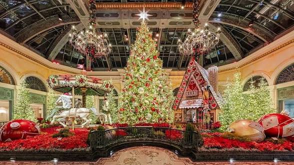 Bellagio Conservatory decorated for Christmas with a towering tree, gingerbread house, and poinsettias